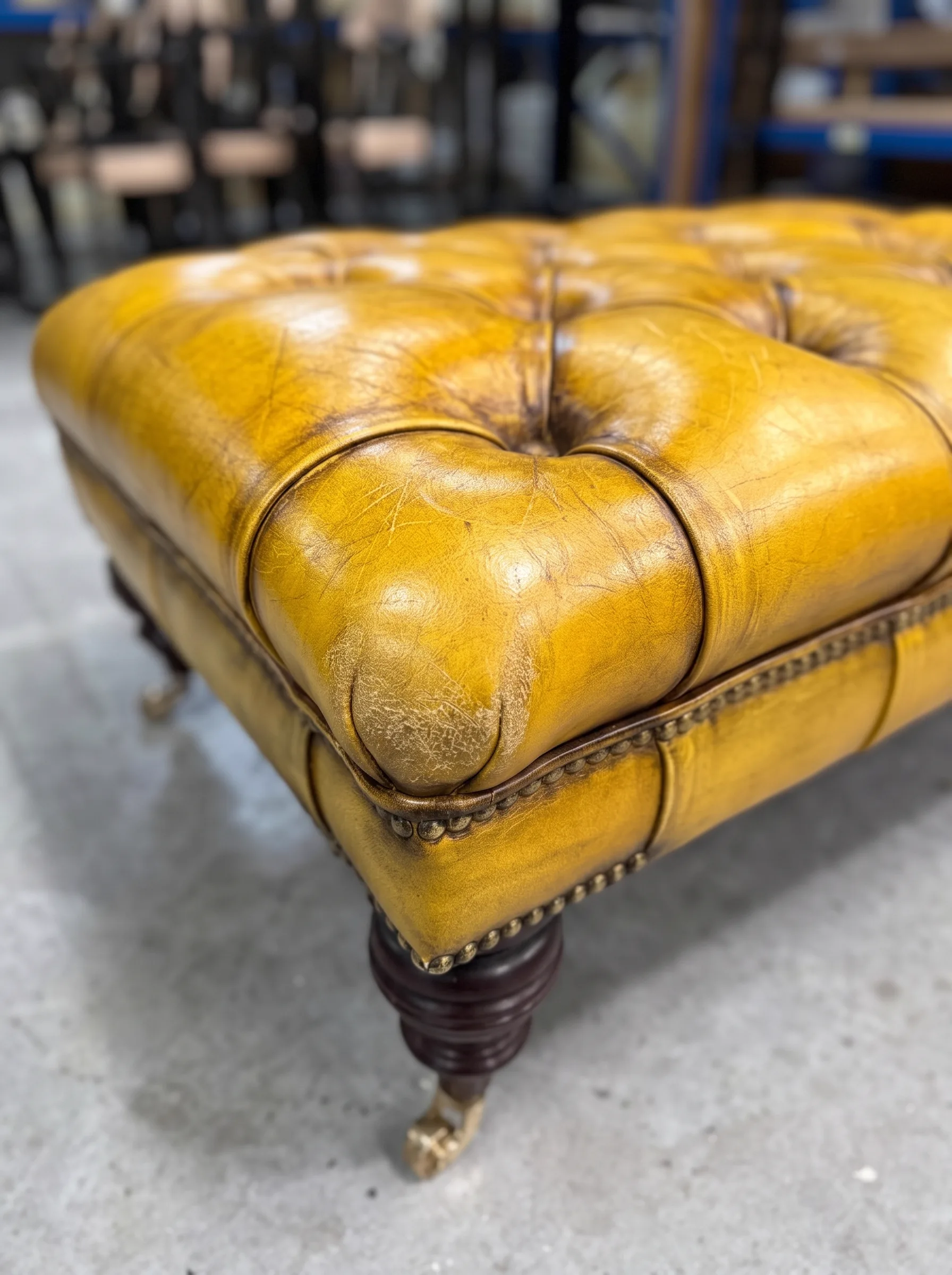 Cracked, dry mustard-tan buttoned leather footstool before restoration
